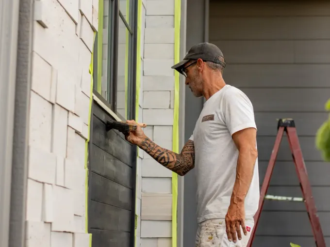 Exterior painting preparation in Costa Rica — worker priming a rendered wall surface before the finish coat
